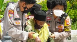 Salah satu warga lansia dibantu aparat kepolisian antusias mengikuti Program Vaksinasi Covid-19 yang digelar Polri di Graha Wangsa, Bumi Waras, Selasa (11/1). Foto: Netizenku.com