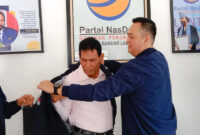 Ketua DPD Partai NasDem Bandarlampung, Naldi Rinara S Rizal, mengenakan jaket NasDem kepada Barlian Mansyur, Selasa (11/1). Foto: Netizenku.com