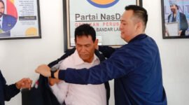 Ketua DPD Partai NasDem Bandarlampung, Naldi Rinara S Rizal, mengenakan jaket NasDem kepada Barlian Mansyur, Selasa (11/1). Foto: Netizenku.com