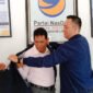 Ketua DPD Partai NasDem Bandarlampung, Naldi Rinara S Rizal, mengenakan jaket NasDem kepada Barlian Mansyur, Selasa (11/1). Foto: Netizenku.com