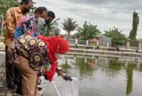 Wali Kota Bandarlampung Eva Dwiana menabur benih ikan di Embung KORPRI Sukarame, Kamis (10/2). Foto: Netizenku.com
