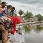 Wali Kota Bandarlampung Eva Dwiana menabur benih ikan di Embung KORPRI Sukarame, Kamis (10/2). Foto: Netizenku.com