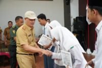 Sekdakab Tubaba Ir. Novriwan Jaya, SP menyerahkan secara simbolis piagam pelatihan Wawasan Kebangsaan Kesadaran Bela Negara yang di Selenggarakan Kesbangpol Tubaba di Wisma Asri, Tiyuh Tirta Makmur, Senin (3/6/2024). (Arie/NK)