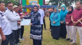 Kepala BNN Kabupaten Tanggamus, Diani Indramaya, menyerahkan SK Desa Bersinar Kabupaten Tanggamus dalam gelaran peringatan Hari Anti Narkotika. (Rapik/NK)