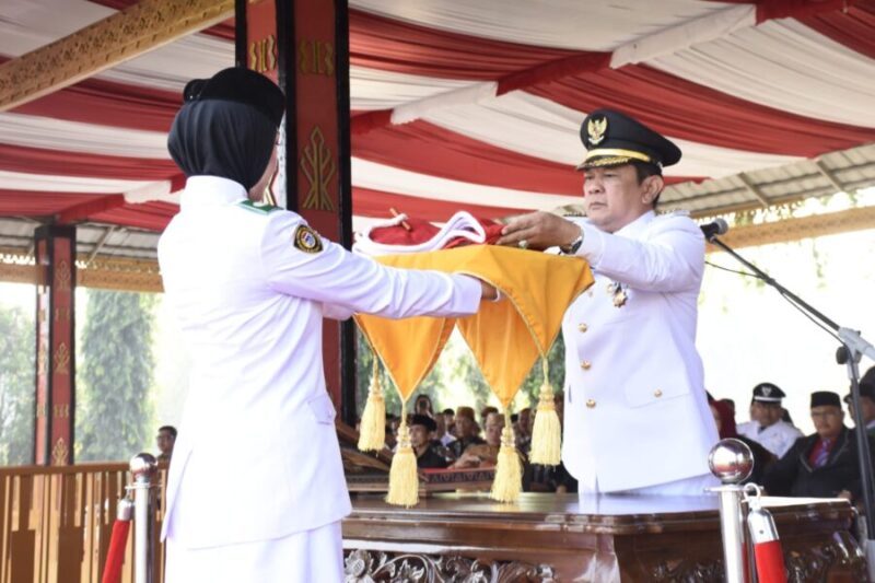 Pj. Bupati Tubaba Drs. M. Firsada, M.Si menyerahkan Sang Saka Merah Putih kepada Paskibraka Tubaba untuk di kibarkan, Sabtu (17/8/2024). (Ist/NK)