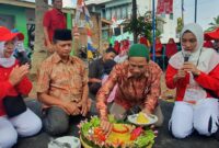 Tokoh agama RT 01 Sumberrejo, Pungut, memotong tumpeng pada perayaan HUT ke-79 RI, didampingi Ketua RT, Izul Gunawan.