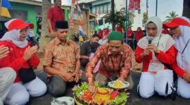 Tokoh agama RT 01 Sumberrejo, Pungut, memotong tumpeng pada perayaan HUT ke-79 RI, didampingi Ketua RT, Izul Gunawan.