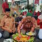 Tokoh agama RT 01 Sumberrejo, Pungut, memotong tumpeng pada perayaan HUT ke-79 RI, didampingi Ketua RT, Izul Gunawan.