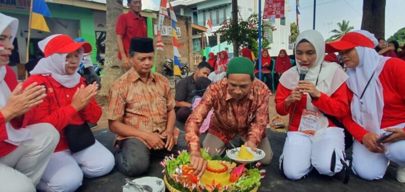 Tokoh agama RT 01 Sumberrejo, Pungut, memotong tumpeng pada perayaan HUT ke-79 RI, didampingi Ketua RT, Izul Gunawan.