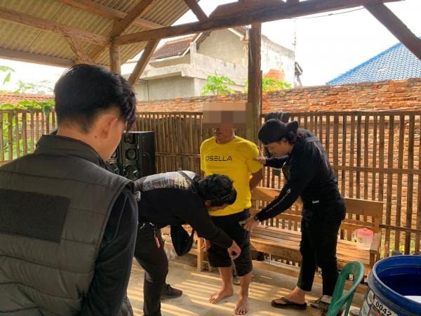 Polisi menggeledah badan tersangka EB alias Bakar (kaos kuning) di di Pekon Sukoharjo 3, Kecamatan Sukoharjo, Kabupaten Pringsewu pada Senin (16/9/2024). 