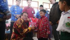 Penjabat bupati Lampung Barat, Nukman membagikan bantuan seragam gratis kepada siswa-siswi di Lampung Barat. (Iwan/Nk)