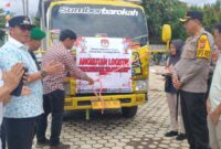 Pj bupati Lampung Barat Nukman dan Kapolres AKBP Rinaldo Aser menyaksikan pemotongan pita sebagai tanda pelepasan kendaraan distribusi logistik Pilkada, Minggu (24/11/2024). (Iwan/Nk)