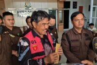 Sekretaris Kabupaten Pringsewu, Heri Iswahyudi, tersenyum lebar pasca ditetapkan tersangka korupsi dana hibah LPTQ 2022. (Ist/Netizenku) 